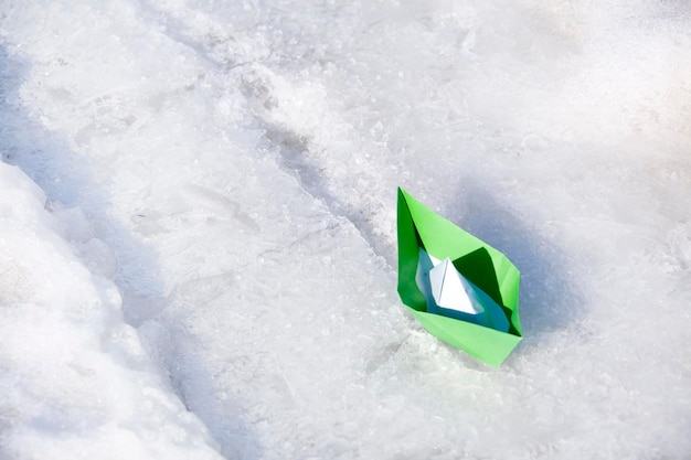 Bateau en papier vert sur la neige