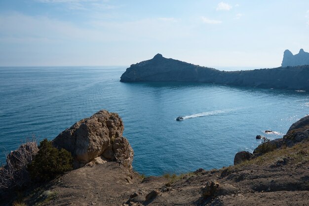 Bateau avec passagers en mer, vacances d'été, voyage en yacht au milieu des rochers et des montagnes, paysage marin