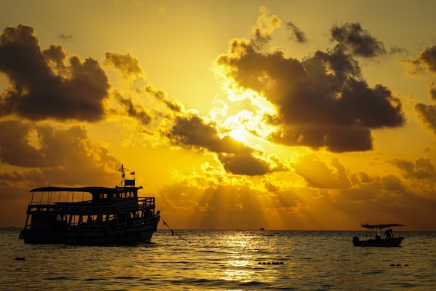 Bateau de pêche chalutier et pêcheur sur l'eau océan et ciel nuages dramatiques au lever du soleil - bateau de pêche mer au coucher du soleil silhouette aube