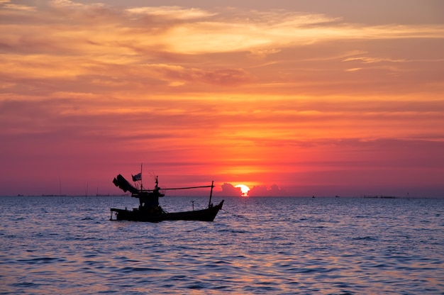 Un bateau de pêcheur avec pendant le coucher du soleil