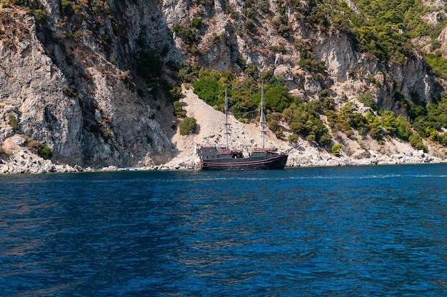 Un bateau pirate est amarré dans une baie avec une montagne en arrière-plan