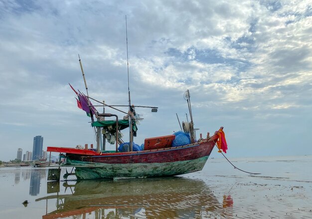 Un bateau sur la plage avec un ciel nuageux en arrière-plan.