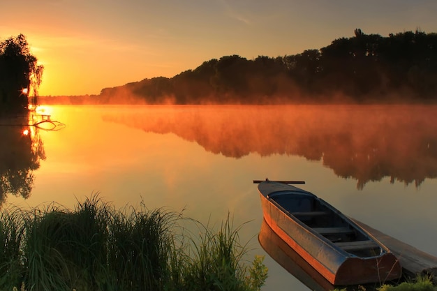 Bateau sur la rive d'un lac brumeux un matin d'été