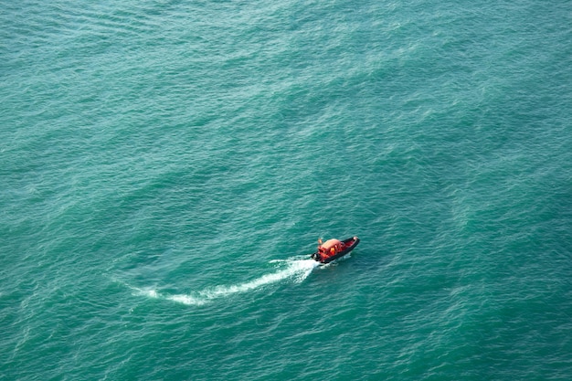 Bateau rouge dans le beau fond de la mer bleue