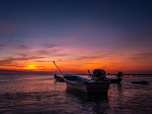 Bateau en silhouette en mer contre le ciel au coucher du soleil