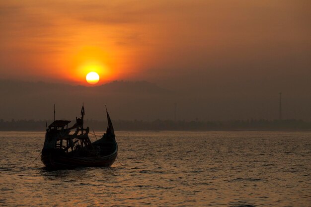 Photo bateau en silhouette en mer contre le ciel au coucher du soleil