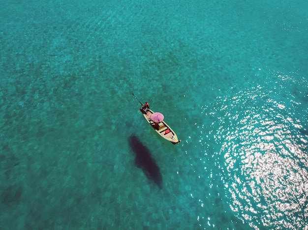 Un bateau solitaire flotte paisiblement au milieu d'un vaste océan bleu, vue aérienne