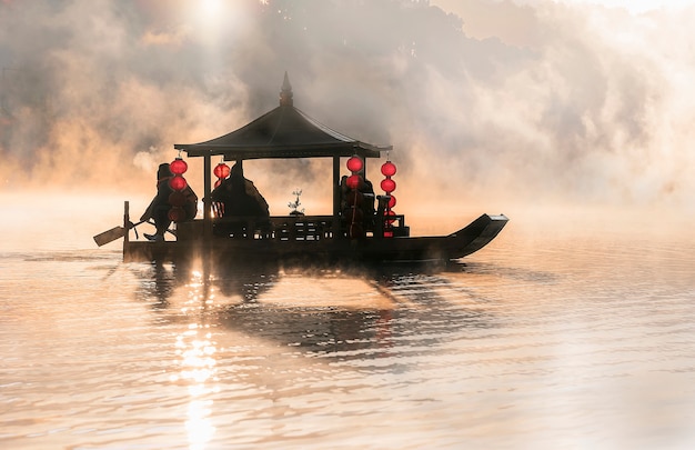 Bateau de style chinois dans le lac avec la lumière du matin et le brouillard.