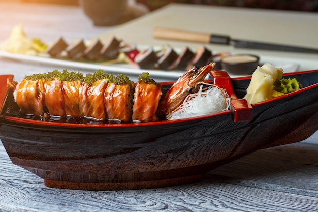 Bateau de sushi au gingembre. Rouleaux de sushi et nouilles. Rouleaux d'Uramaki avec garniture spéciale. Repas traditionnel au café japonais.