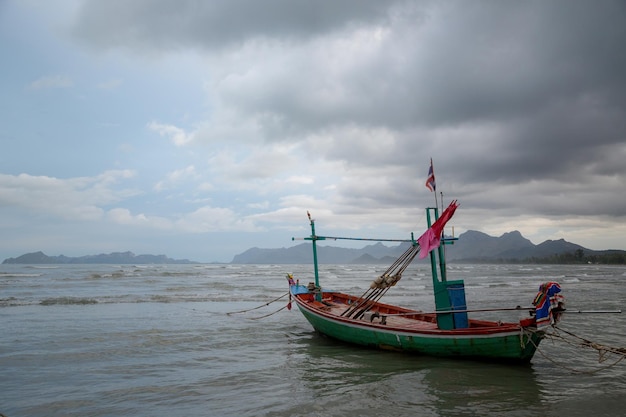 Bateau thaïlandais à longue queue à marée basse dans l'océan avec des montagnes carst en arrière-plan et cloudscape à Thaïlande Asie