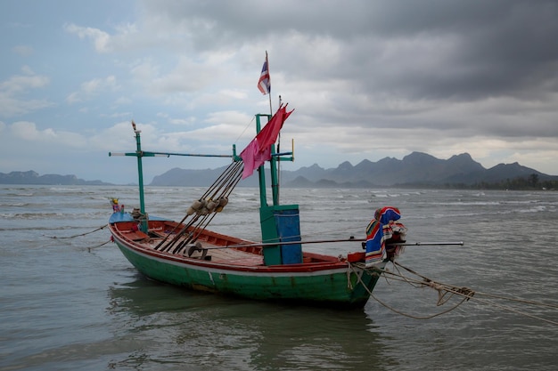 Bateau thaïlandais à longue queue à marée basse dans l'océan avec des montagnes carst en arrière-plan et cloudscape à Thaïlande Asie