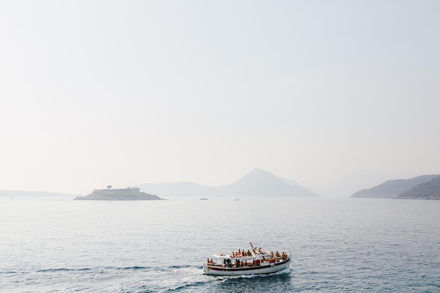 Un bateau avec des touristes navigue vers l'île de Mamula au Monténégro