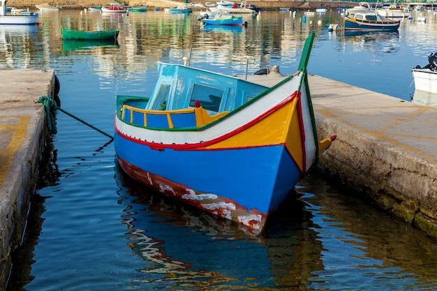 Le bateau traditionnel maltais nommé luzzu est amarré entre deux plaques de pierre