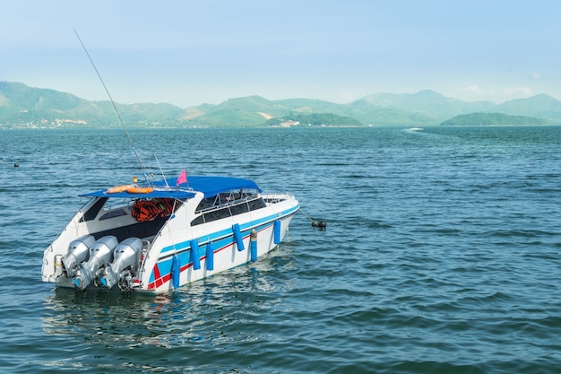 Bateau de vitesse blanche à la mer avec le fond de la montagne.