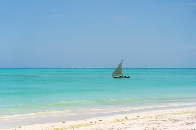 Bateau à voile et ciel bleu au-dessus des vagues d'eau de mer sur l'île de Zanzibar, Tanzanie, Afrique de l'Est. Concept de voyage et de nature