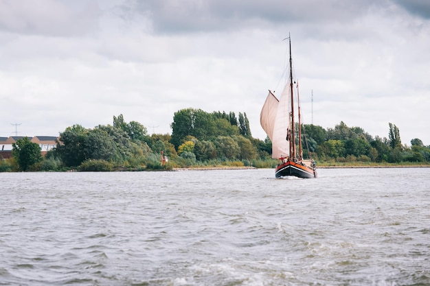 Un bateau avec une voile dessus navigue dans l'eau.