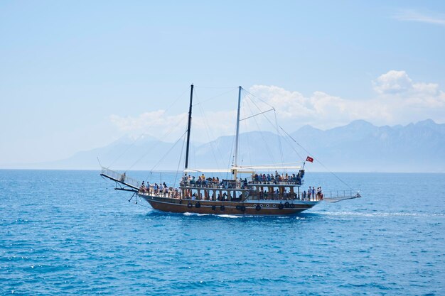 Photo bateau à voile sur la mer méditerranée bleue avec beaucoup de touristes profitant de vacances