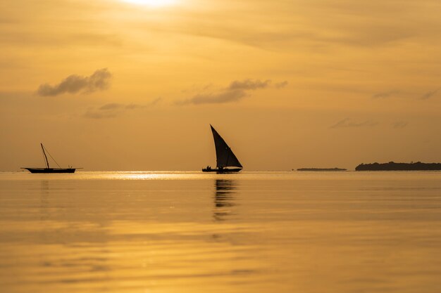 Bateau à voile de pêche traditionnelle pendant le coucher du soleil sur l'océan Indien dans l'île de Zanzibar, Tanzanie, Afrique