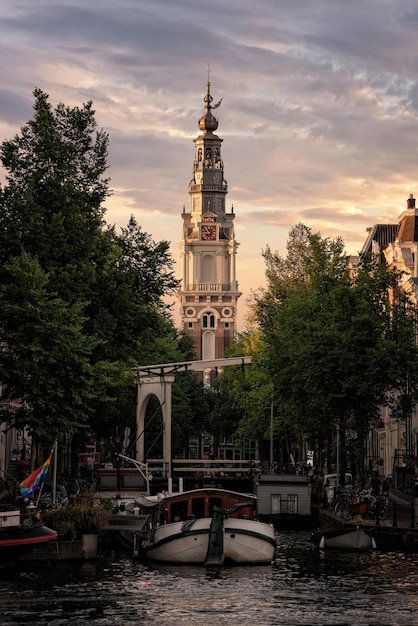 Des bateaux amarrés sur le canal contre l'église de la ville au coucher du soleil