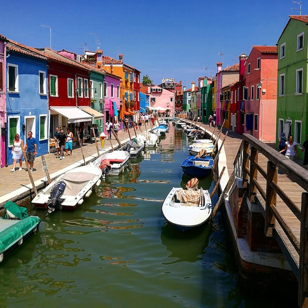 Des bateaux amarrés sur le canal par des gens sur le sentier au milieu des bâtiments