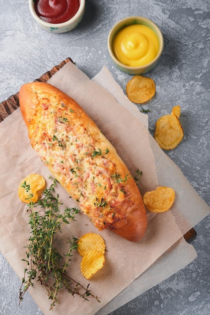 Bateaux à baguette Sandwich cuit au four chaud sur pain baguette avec jambon bacon légumes et fromage sur parchemin et support en bois sur fond de béton gris Vue de dessus Espace de copie