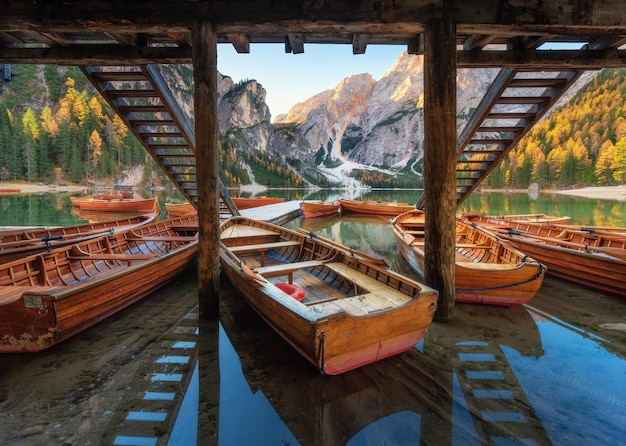 Bateaux en bois près de la maison dans le lac de Braies au lever du soleil en automne dans les Dolomites Italie Scène avec montagnes jetée bateau célèbre lac réflexion arbres en automne Voyage en Europe Alpes italiennes des Dolomites