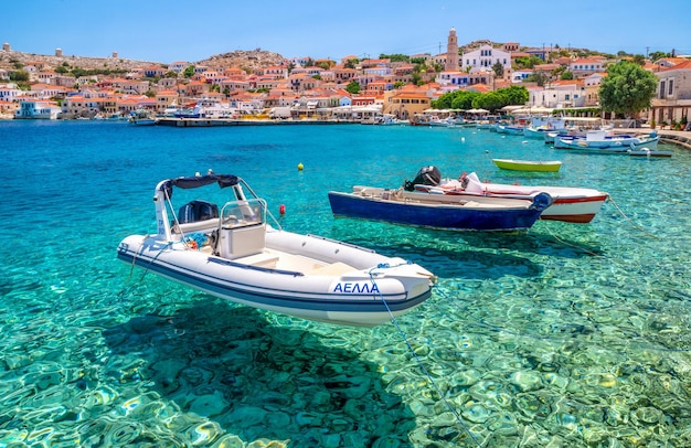 Bateaux sur la mer Égée claire dans le port du village de pêcheurs de l'île de Halki Chalki en Grèce