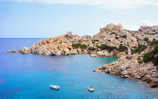 Bateaux sur la mer Méditerranée près des montagnes de Capo Testa à Santa Teresa Gallura, Sardaigne, Italie. Navire et eau bleue.