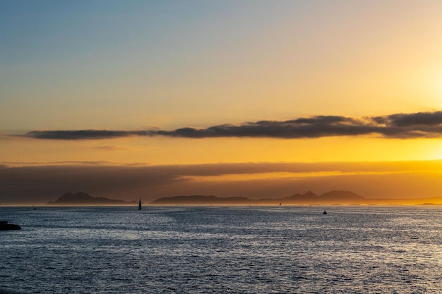 Des bateaux naviguant dans la Ria de Vigo en Galice au coucher du soleil avec les îles Cies en arrière-plan