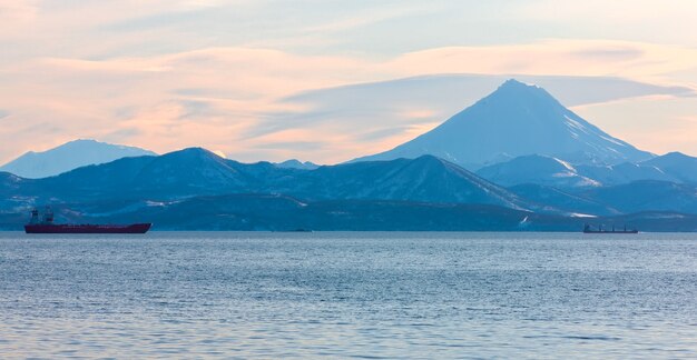 Les bateaux de pêche dans la baie avec le volcan du Kamtchatka