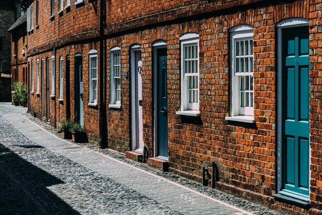 Bâtiment en brique sur une rue pavée avec des portes en bois et des fenêtres blanches à Farnham, en Angleterre