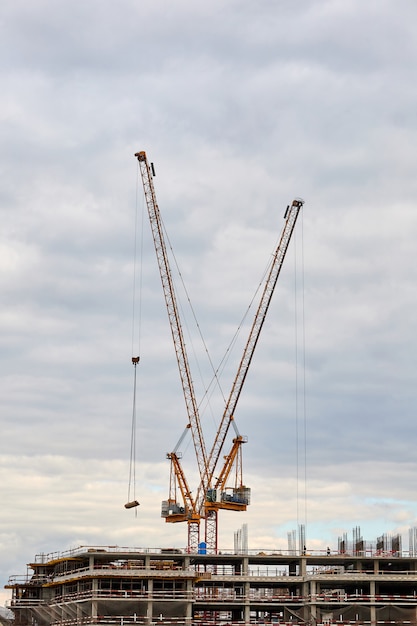 Bâtiment en construction et grues à tour contre le ciel