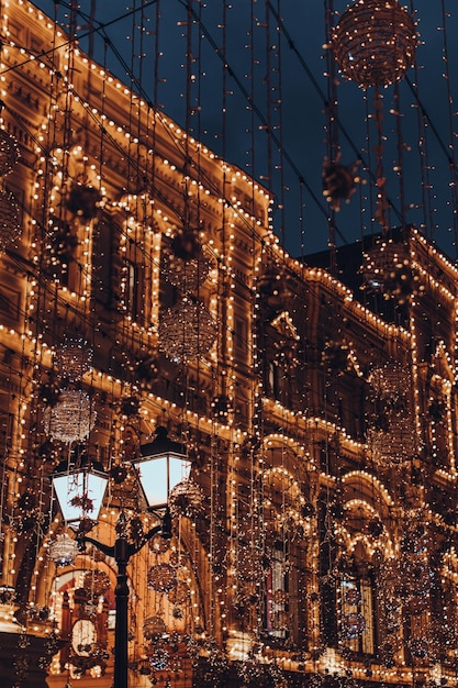 Bâtiment décoré de guirlandes festives dorées Noël et nouvel an dans la ville du soir