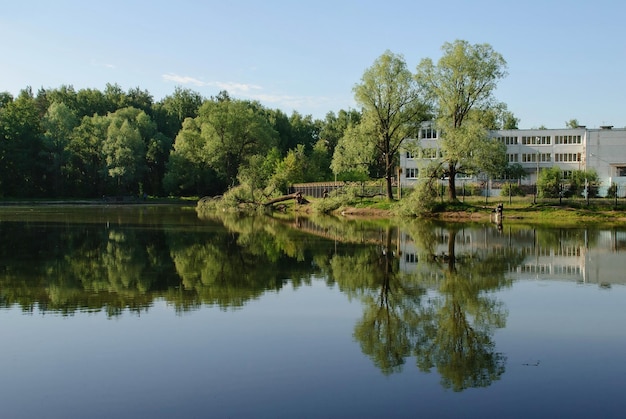 Le bâtiment de l'école se reflète dans l'eau d'un petit étang un matin ensoleillé