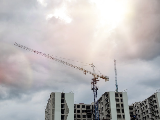 Bâtiment avec grue dans le chantier de construction sous des nuages ​​sombres