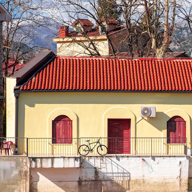 Un bâtiment jaune avec un toit rouge et un vélo sur le balcon.