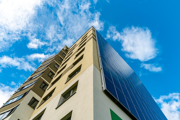 Un bâtiment moderne à haut rendement énergétique sur fond de nuages Bâtiment résidentiel à plusieurs étages avec panneaux solaires au mur Sources d'énergie renouvelables dans la ville