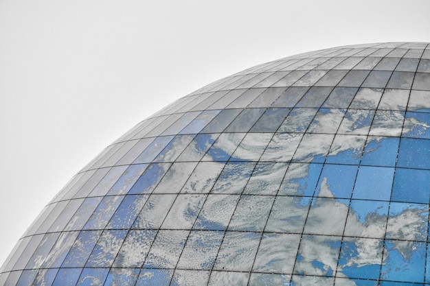Bâtiment moderne sphérique en verre avec reflet du ciel bleu et des nuages. Gros plan, copiez l'espace, isolé.