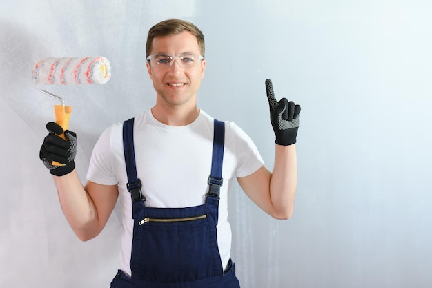 Bâtiment de réparation et concept de maison gros plan d'un homme dans des gants tenant un rouleau de peinture