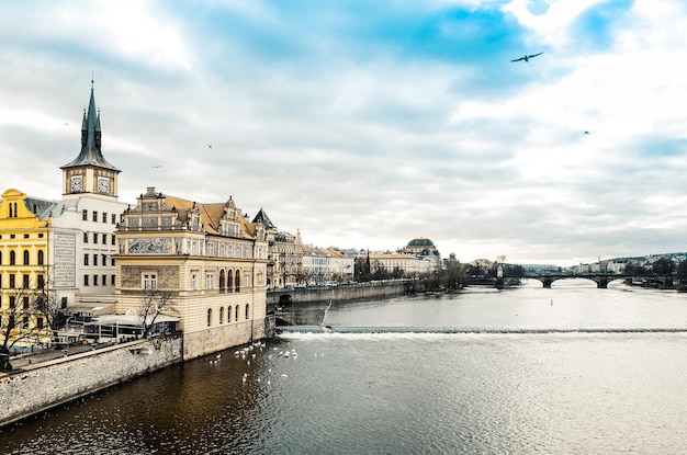 Des bâtiments au bord de la rivière Vltava contre un ciel nuageux