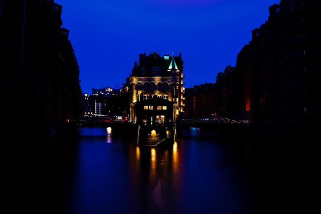 Photo des bâtiments éclairés au bord d'une rivière la nuit