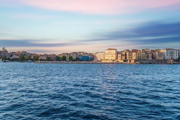 Bâtiments de l'île de Corfou sur le rivage et l'eau de mer au coucher du soleil