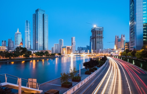 Bâtiments modernes et circulation urbaine des deux côtés de la rivière haihe à tianjin la nuit