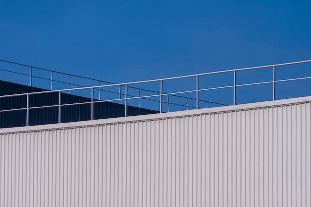 Bâtiments d'usine en acier ondulé blanc et noir avec clôture en aluminium sur le toit contre le ciel bleu