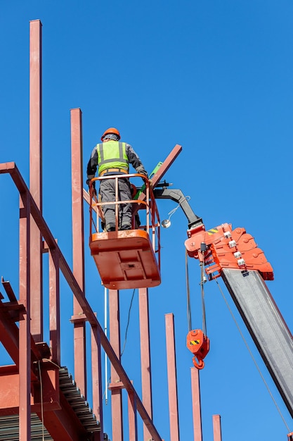 Photo les bâtisseurs travaillent en hauteur dans un berceau de levage pour créer la charpente en fer du bâtiment