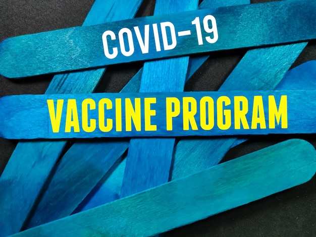 Photo bâton en bois bleu avec texte programme de vaccin covid 19 sur fond noir concept médical