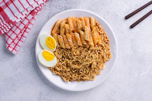 Bâton de gâteau de riz coréen tteokbokki avec nouilles et œuf à la coque dans une sauce épicée cuisine de rue coréenne.