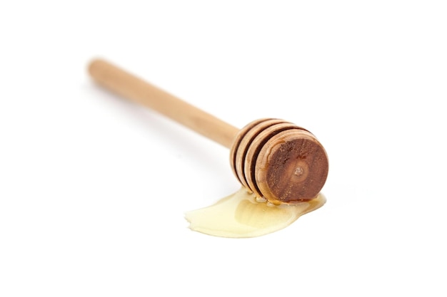 Bâton de miel en bois avec goutte isolé sur blanc