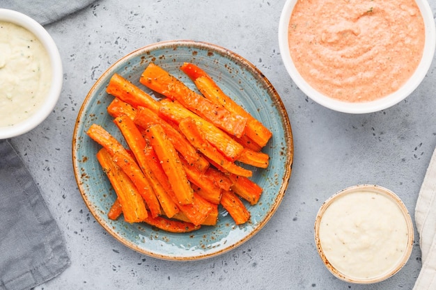 Bâtonnets de carottes de saison au four avec sauce et houmous Aliments sains végétariens Vue de dessus à plat