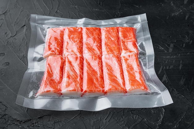 Bâtonnets de chair de poisson de crabe dans un emballage sous vide, sur fond noir